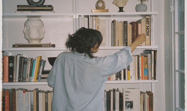 Kvinna som står framför en bokhylla.