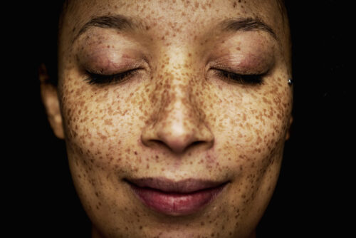 En närbild på en kvinnas ansikte, hon blundar med ett leende på läpparna.