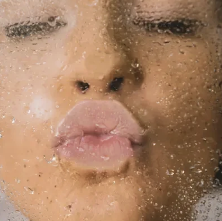 Kvinna som gör pussmun på en våt duschvägg.