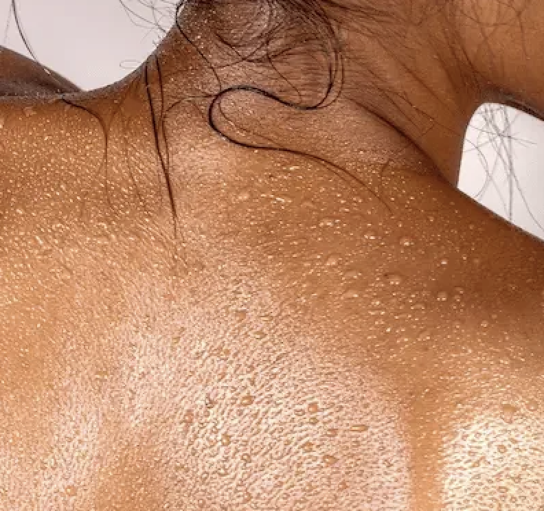 En kvinna fotad bakifrån med droppar på ryggen. Halvkropp.