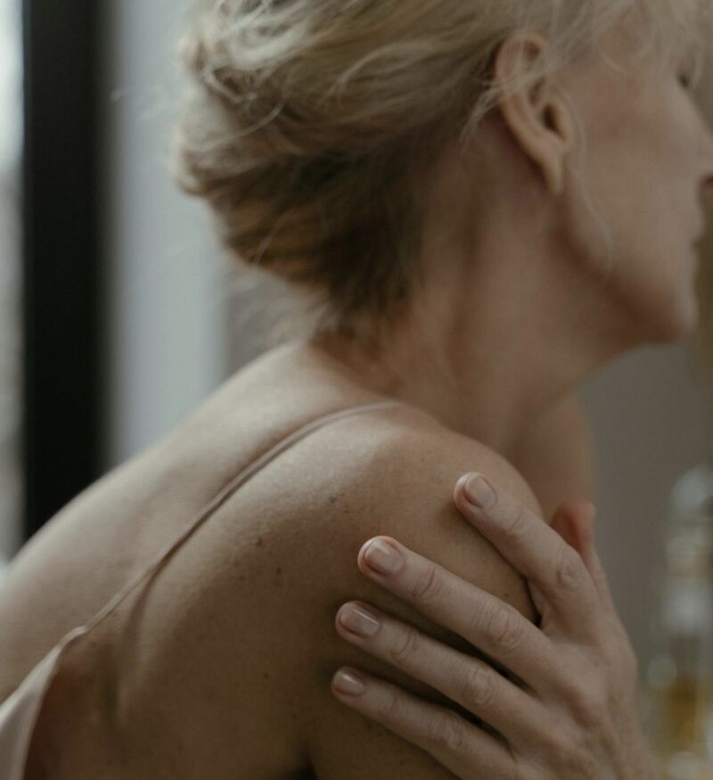 Kvinna fotad från sidan som håller om sig själv.