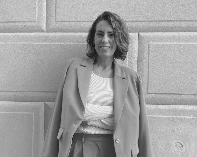 Bild på Nina Campioni som berättar om hur hon kom i klimakteriet vid 39 årsålder. Hon har kort, vågigt brunt hår. Hon ler och har armarna i kors och en kavaj över axlarna.