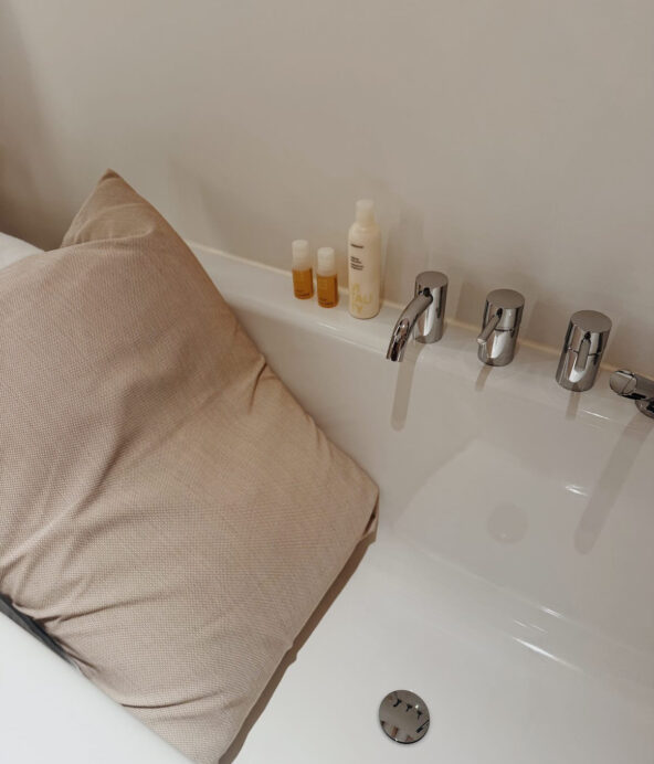 Badkar med en kudde i för komfort. På kanten står lyxiga skönhetsprodukter.