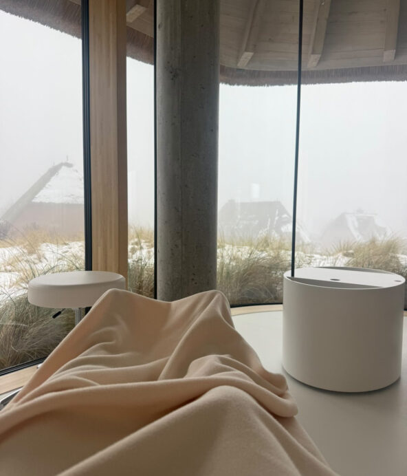 Utsikten från Lanserhof.Man ser stora fönster och personen som tagiit bilden har en ljus filt virad runt ben och fötter.