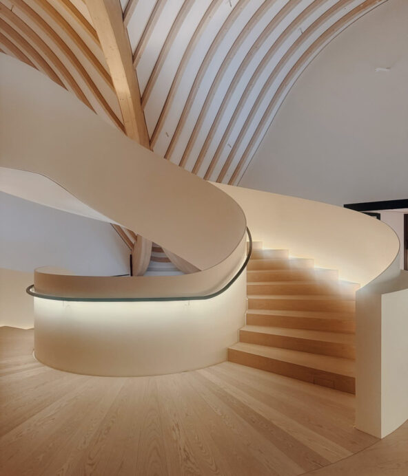 En stor och bred spiraltrappa i vitt och trä, inne på Lanserhof hälsoretreat.