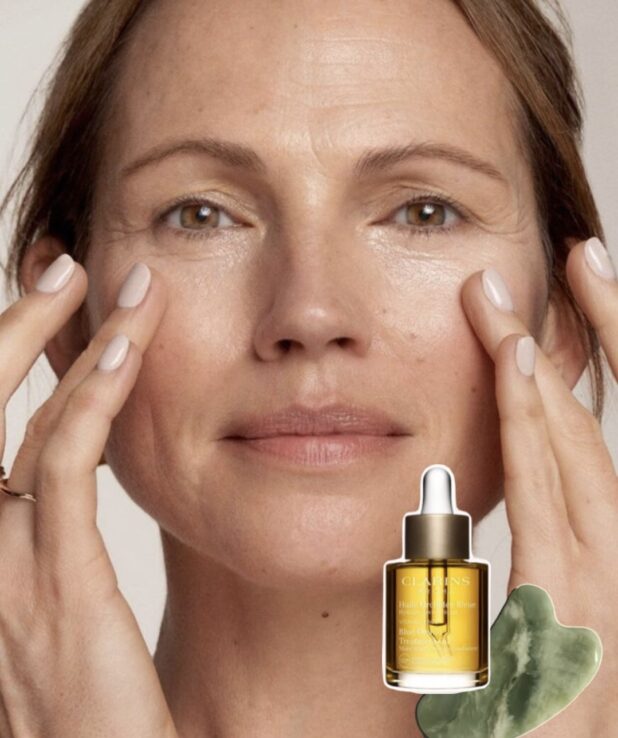 Kvinna med osminkat ansikte som håller händerna upp mot ansiktet.