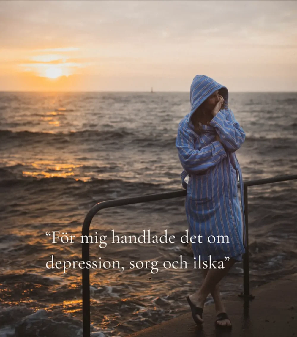Kristin Lagerqvist står vid havet i solnedgång med en blå och röd randig badrock.