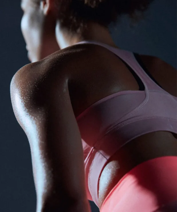 Kvinna som tränar, man ser henne bakifrån och hon har starka armar är svettig av träningen.