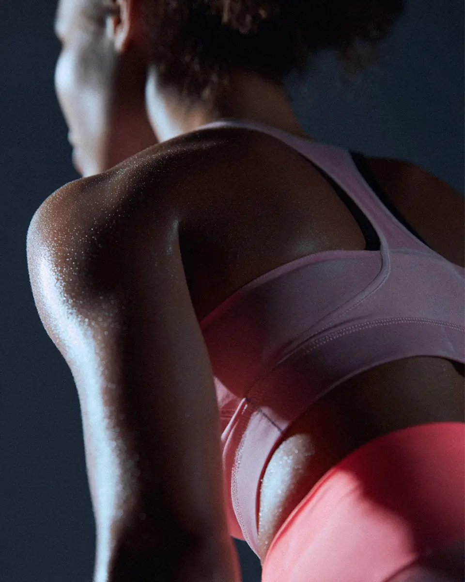 Kvinna som tränar, man ser henne bakifrån och hon har starka armar är svettig av träningen.