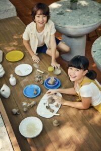 Två glada barn som sitter och leker med lera och skapar olika figurer.