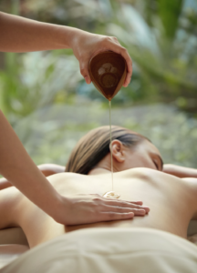 En kvinna som får massage, hon ligger på mage och får en massageolja på ryggen.