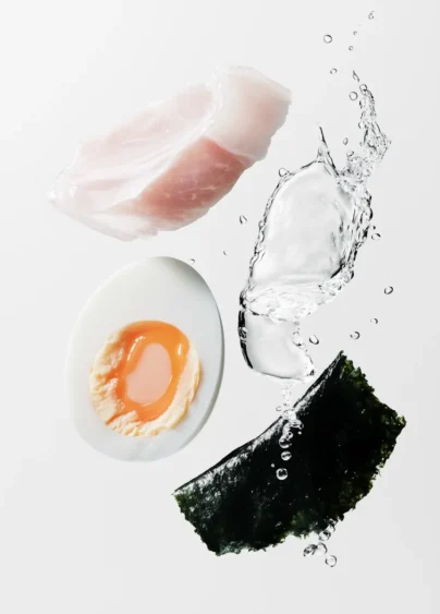 Närbild på en vit fiskbit, ett halvt ägg, sjögräs och vatten, bilden är gjord med AI.