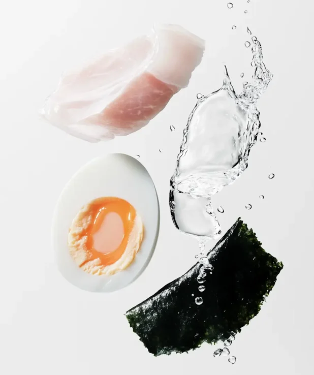 Närbild på en vit fiskbit, ett halvt ägg, sjögräs och vatten, bilden är gjord med AI.