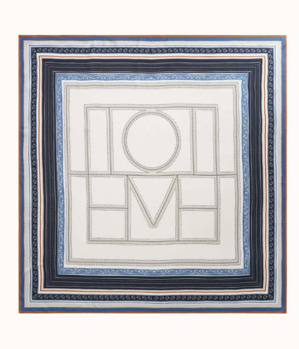 mönstrad scarf från Toteme med logga på. Färgerna går i blått, svart, vitt och orange.